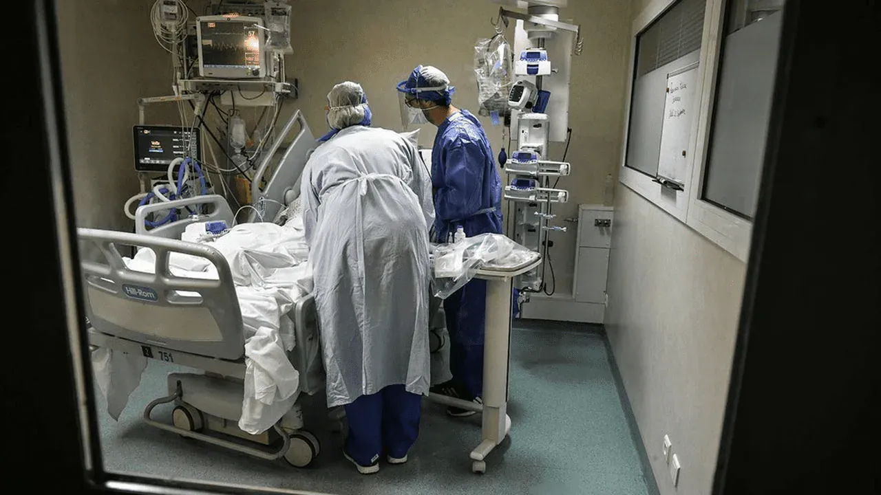 Equipa médica a cuidar de um doente numa sala de cuidados intensivos repleta de equipamentos monitorizados
